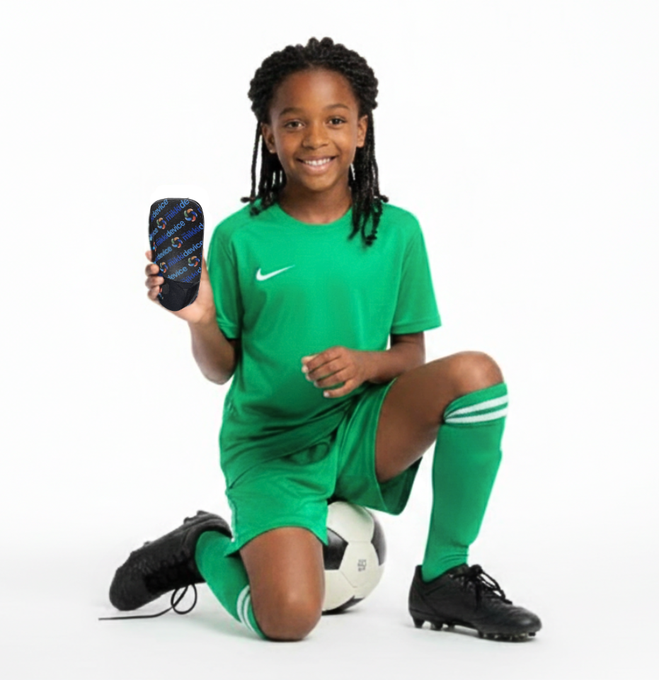 soccer girl player holding mikki device orthotic while sitting on the floor on her soccer ball